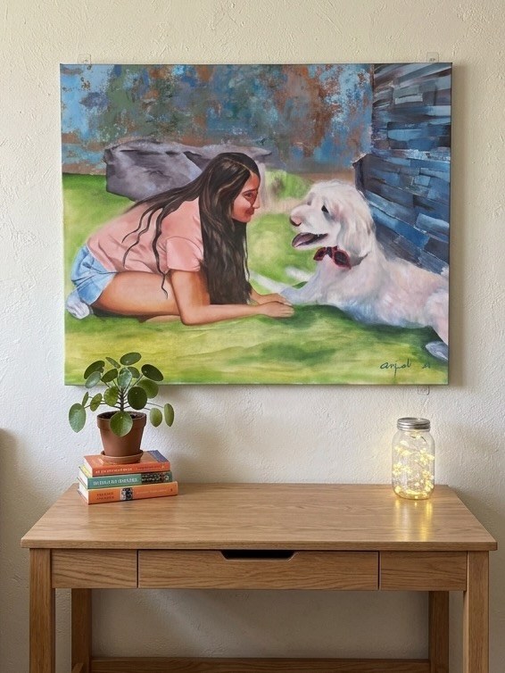 Girl lying on the grass facing a white dog